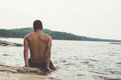 男人穿黑色短裤坐在海岸线
